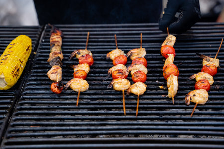 A delicious outdoor grill showcasing an enticing array of shrimp, juicy tomatoes, and sweet corn on...