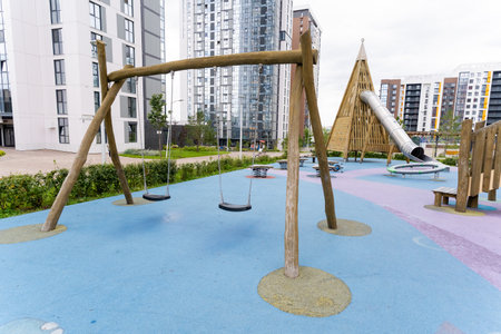 A vibrant playground equipped with colorful swings and a fun slide located in front of a modern...