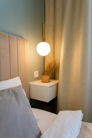 In this modern bedroom corner, there is a minimalist nightstand paired harmoniously with a...