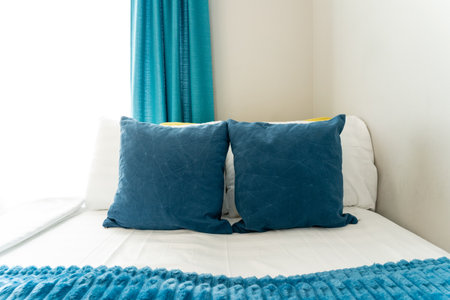 In a cozy bedroom, there lies a comfortable bed adorned with soft blue pillows and a matching blue blanket, creating a calming and serene atmosphere that invites relaxation and peaceの写真素材