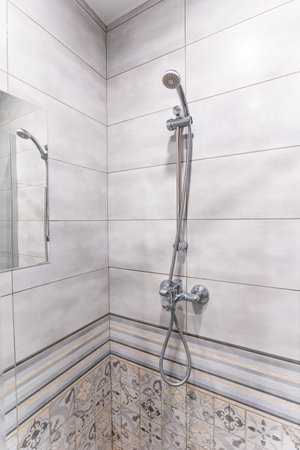 This is a bathroom that features a modern shower head, along with a stylish mirror that enhances its...