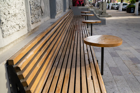 A beautifully designed wooden bench, complete with attached tables, is situated on the lively...