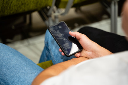 An individual is holding a modern cell phone firmly in their hand while experiencing the latest...