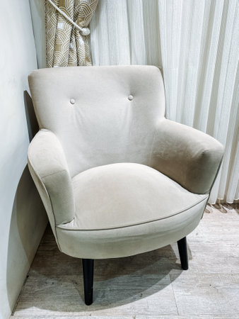 A lovely white chair by a large window fills the cozy room with natural light, creating a warm, calming atmosphere that fosters relaxation and comfort for everyone who enjoys the spaceの写真素材