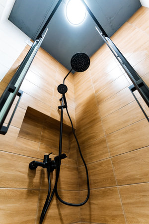 Within the confines of the bathroom, there is a shower head that is elegantly suspended from the ceiling, which enhances both the modern style and the practical functionality of the overall spaceの写真素材