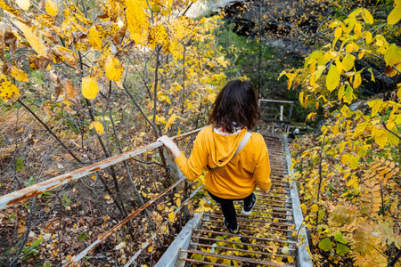A woman wearing a bright yellow hoodie strolls down the stairs, completely absorbed in the vibrant...