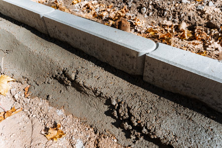 This image shows freshly poured concrete and curb stones at an active construction site, highlighting the groundwork essential for urban infrastructure developmentの写真素材
