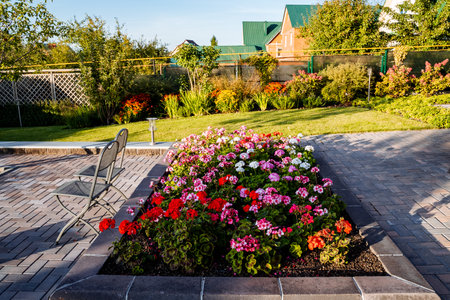 There is a beautiful garden filled with a multitude of colorful flowers, and in the background, a charming house can be seenの写真素材