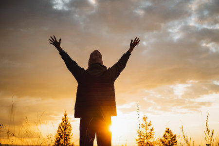 A beautiful and serene sunset scene showcases an individual with outstretched arms, reveling in a moment of pure joy and deep connection to the breathtaking beauty of natureの写真素材