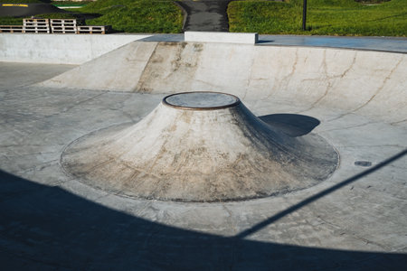 A skate park featuring a unique cone-shaped ramp located prominently in the center area, surrounded...