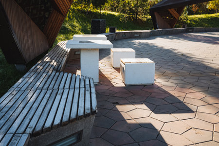 There is a charming wooden bench accompanied by a table and comfortable ottomans situated in a...