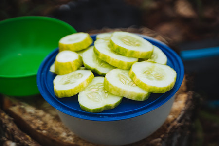 Enjoy a vibrant display of freshly sliced cucumbers arranged in a bowl, perfect for summer picnics and healthy snacks in natureの写真素材