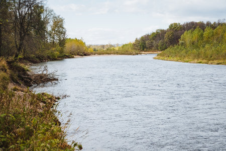 A river winds through a stunning landscape of vibrant autumn foliage, creating an ideal spot for nature lovers and outdoor enthusiasts seeking tranquility and beautyの写真素材