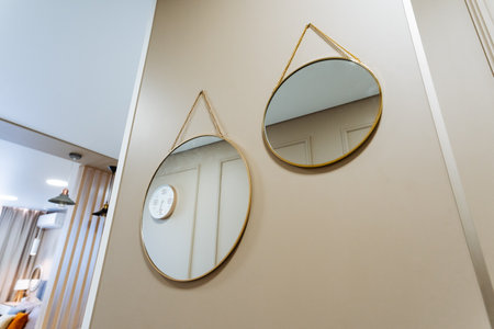 Two circular mirrors are elegantly hanging on a wall in a narrow hallway, reflecting the light and adding a touch of style to the spaceの写真素材