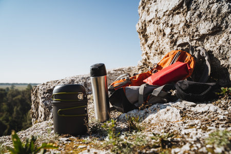 A sturdy backpack along with a thermos is sitting on top of a large rock, overlooking the...