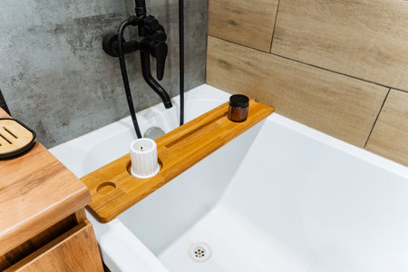 This elegantly and beautifully designed bathtub showcases a stunning wooden tray positioned on the side, which adds a lovely touch of relaxation and enhances the overall enjoyable bathing experienceの写真素材