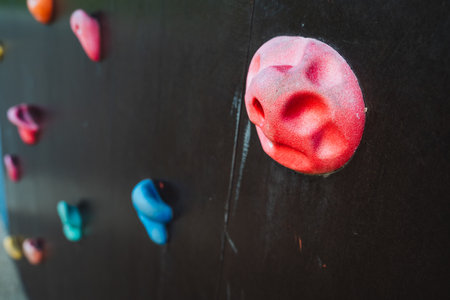 This closeup image of a climbing wall shows vibrant holds and uniquely shaped rocks, each with distinct textures and colors, creating an exciting experience for outdoor enthusiastsの写真素材