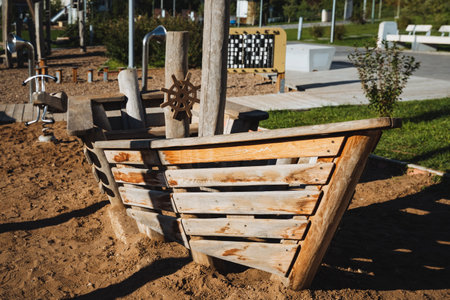 A wooden boat, complete with a steering wheel, is currently resting idle in the warm, golden sand.の写真素材