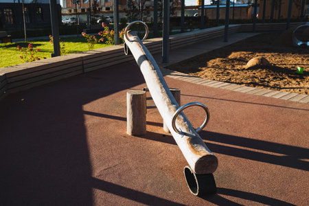 In a peaceful park, there is a lovely wooden seesaw that is resting on the ground, surrounded by beautiful grass and trees, providing a perfect place for children to play and have funの写真素材