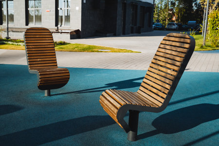 Two sturdy wooden chairs are sitting comfortably on a vibrant blue carpet, providing a perfect spot for relaxation and leisure in an outdoor setting surrounded by natureの写真素材