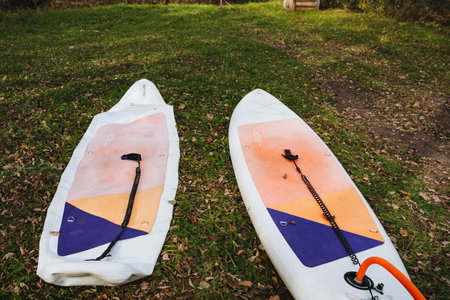 Two SUP boards are lying on the grass, the process of pumping air into a board with a paddle. High...