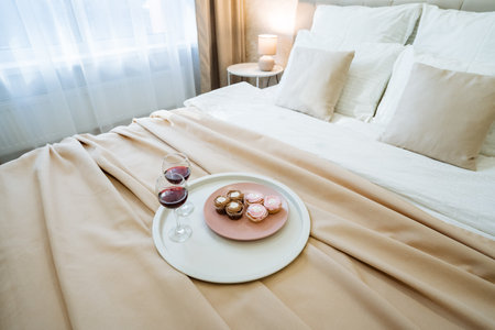 A beautifully arranged bed featuring a plate of delicious food and two elegant glasses of wine...
