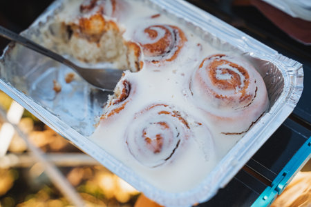 A beautifully arranged tray filled with delicious cinnamon rolls, complemented by a spoon resting in it, ready to serve and enjoy the delightful treats inside. Perfect for any occasionの写真素材