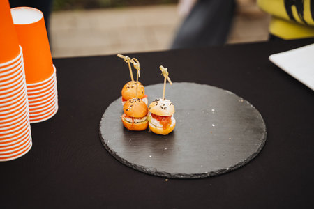On a table sits a sleek black plate that beautifully displays three delicious appetizers artfully arranged on it, creating an inviting sight for anyone who loves delightful cuisineの写真素材