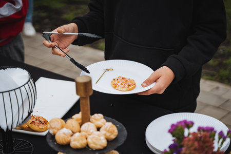 An individual skillfully balances and holds a large, overflowing plate filled with a variety of delicious food, using tongs to prevent any spills and enhance the overall meal experienceの写真素材