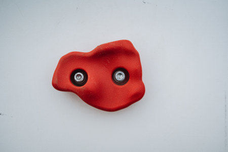 A distinctively red rock featuring two embedded elements is resting on a clean white surface, creating a striking visual contrast that draws attention to the unusual arrangement of objectsの写真素材