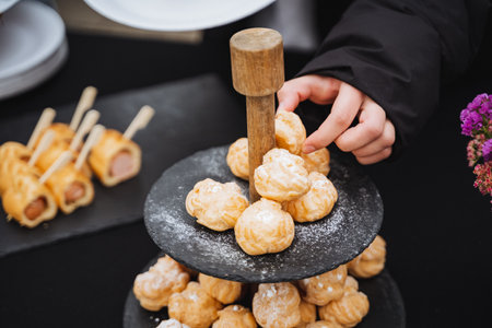 An eager individual extends their hand to grab a delicious pastry sitting on a tray, perfectly illustrating their strong and undeniable desire for the tempting sweet delicacy before themの写真素材