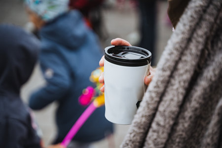 A woman is holding a warm cup of freshly brewed coffee in her hand, leisurely enjoying the rich aroma and delicious flavor as she takes a moment to relax and truly savor this delightful beverageの写真素材