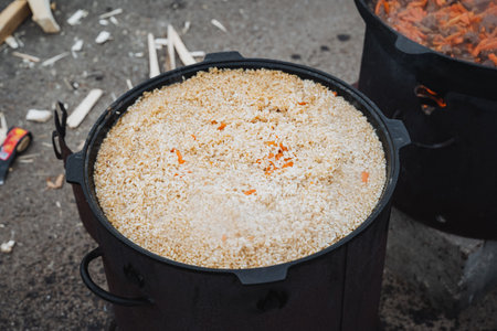 A large pot filled to the brim with rice and vibrant, colorful carrots is sitting on the ground, creating a wonderful scene that captures the essence of homecooked meals and comfort foodの写真素材