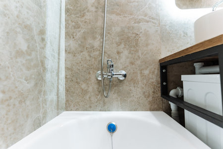 This is a welldesigned bathroom that includes a comfortable bathtub, a sink for washing hands, and a shower area for convenient bathing, all essential fixtures for a complete bathroom experienceの写真素材