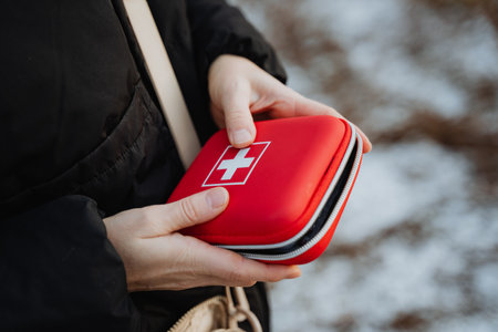 An individual is seen holding a compact red first aid kit while outdoors, which is ideal for...