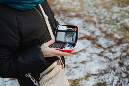 A determined woman is tightly gripping a first aid kit in her hand, fully prepared to tackle any possible medical needs or emergencies that could emerge during her various activities or travelsの写真素材