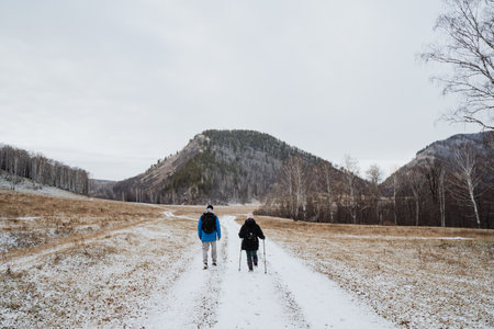 Two hikers joyfully explore a serene winter landscape of snowcovered fields and gentle hills,...