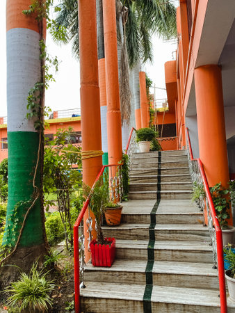 The elegant stairs lead to a striking building with a distinctive red railing, enhancing its aesthetics, while surrounding plants and trees contribute to the delightful outdoor ambianceの写真素材