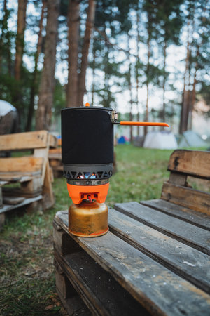 In the serene woods, amidst the surrounding greenery, a stove is carefully placed on a sturdy wooden...