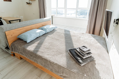 Imagine a cozy bedroom with a plush bed, a stylish couch, a modern TV, and a large window allowing...
