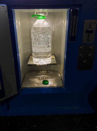 A chilled bottle of refreshing water in a vending machine patiently awaits a thirsty individual...