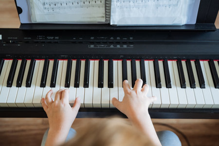An individual is seated at a grand piano, skillfully playing the instrument with both hands gracefully positioned over the keys, producing beautiful melodies that fill the roomの写真素材