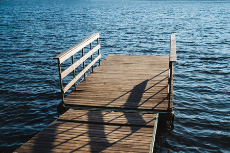 A beautifully crafted wooden dock is positioned right in the middle of a serene and peaceful lake, surrounded by natures splendor and offering a perfect view of the calm and tranquil watersの写真素材