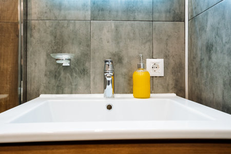 In the elegantly designed bathroom, there is a modern sink complete with a stylish faucet, and next...