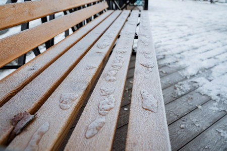 A long and sturdy wooden bench located outside is completely obscured by a thick and heavy layer of snow and ice, making it resemble a picturesque winter wonderland scene during the cold seasonの写真素材