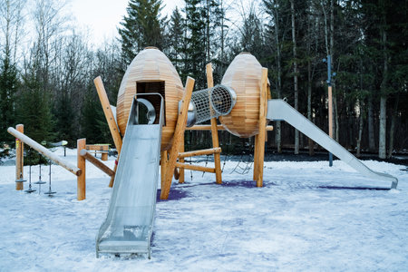 A vibrant playground featuring a colorful slide and a fun tunnel, all beautifully blanketed in soft, glistening snow, creating a perfect winter wonderland for children to enjoyの写真素材