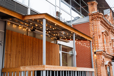 The charming brick building has a lovely wooden porch with twinkling lights, creating a cozy atmosphere ideal for evening relaxation and gatherings with friends and familyの写真素材