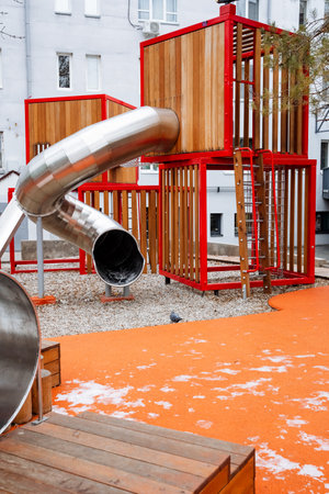 A stainless steel slide is going down a wooden structure in a playgroundの写真素材