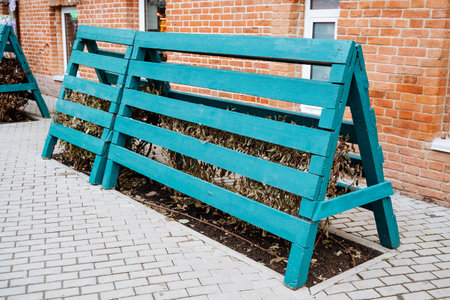 A beautifully crafted blue wooden bench is placed prominently on a neat brick sidewalk, which is situated in front of an attractive brick building, showcasing the perfect outdoor settingの写真素材