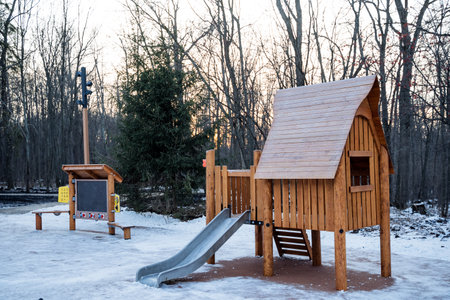 In the midst of pristine white snow, a charming wooden playground adorned with a colorful slide...